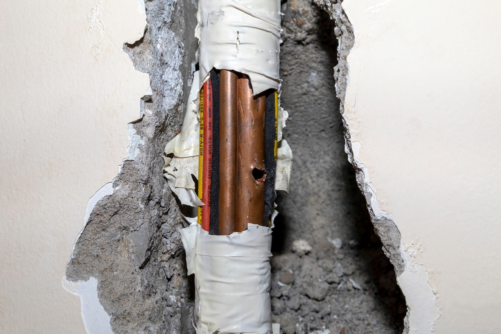Damaged,Copper,Pipe,In,A,Wall,Surrounded,By,Various,Wires Damaged,Copper,Pipe,In,A,Wall,Surrounded,By,Various,Wires